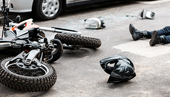 A fallen motorcycle is positioned next to a car after a crash