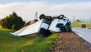 An overturned truck rests on the roadside